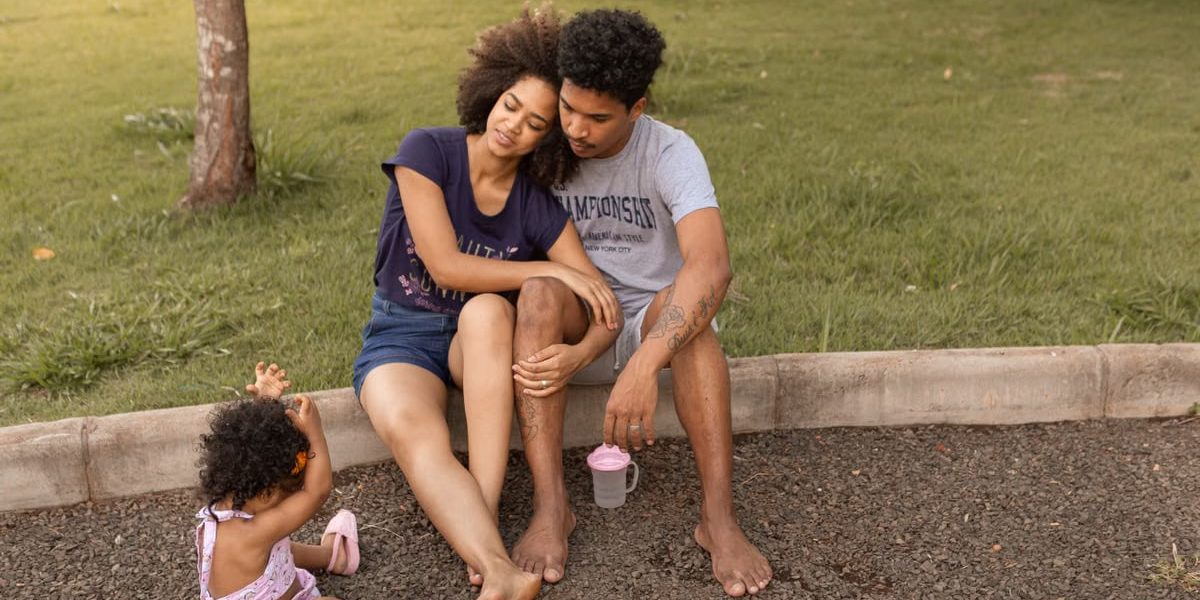 A family enjoys bonding time sitting together on a sunny day in a park.